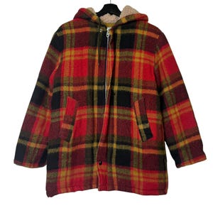 May include: A hooded plaid jacket in red, black, and yellow. The jacket has a full zipper, two front pockets, and a soft, beige lining in the hood. The jacket is hanging on a black hanger.