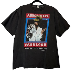 May include: Black vintage t-shirt with a graphic of a woman drinking from a bottle and smoking. The graphic includes the words "Absolutely" and "Fabulous" in red and white, with "100% Sweetie Darling" below.
