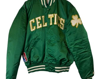 May include: Green satin jacket with the word "CELTICS" in white and gold lettering across the chest. A shamrock patch is on the right sleeve. The jacket has white and green striped trim on the collar, cuffs, and waist.