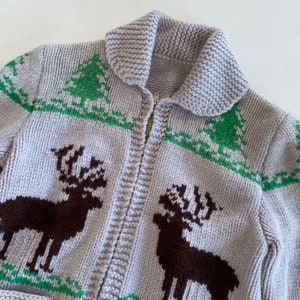May include: A gray knitted cardigan with a zipper closure and a brown and green reindeer pattern.