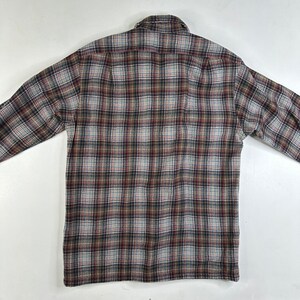 May include: A long-sleeved plaid shirt in brown, white, and blue tones. The shirt has a button-down collar and a button-up front.