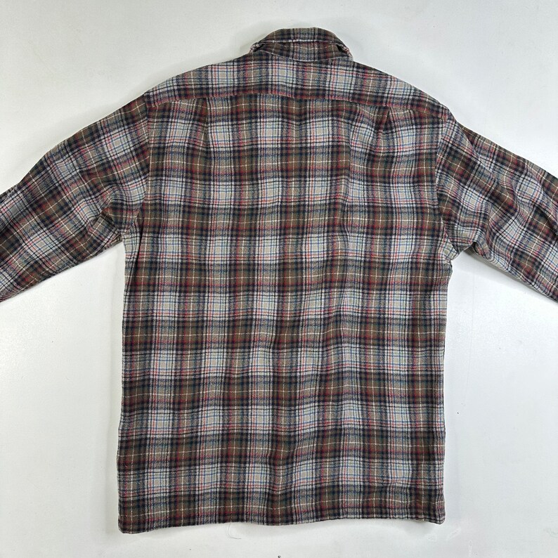 May include: A long-sleeved plaid shirt in brown, white, and blue tones. The shirt has a button-down collar and a button-up front.