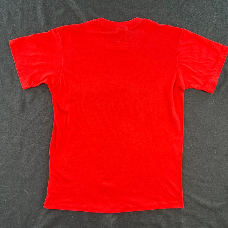 May include: A plain red t-shirt with short sleeves.