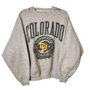Peut inclure: Sweat-shirt gris avec un logo noir et jaune de l'Université du Colorado Buffaloes et le mot "COLORADO" en noir.
