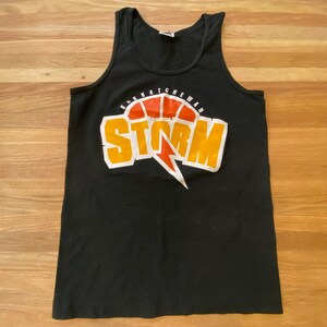 May include: Black tank top with a yellow and orange graphic of a basketball with the text "Saskatchewan Storm" on it.