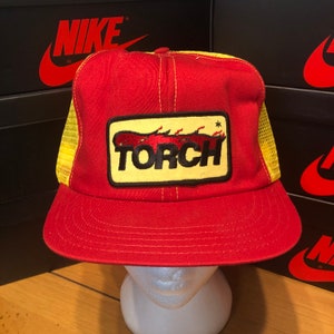May include: Red and yellow trucker hat with a black and yellow patch that says "TORCH" with a red flame design.