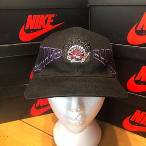 May include: Black baseball cap with a purple and white Toronto Raptors logo and the words "North" and "Black" on the sides.