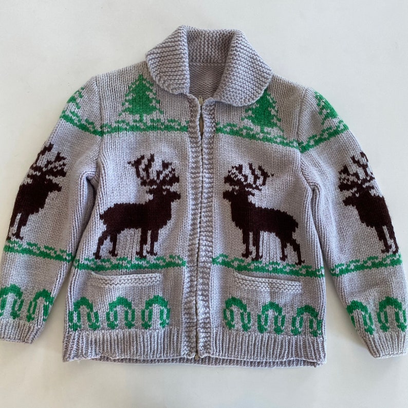 May include: A gray knitted cardigan with a zipper closure and a green and brown reindeer pattern.
