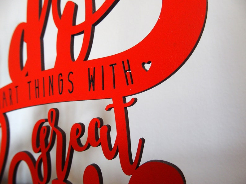 May include: Red wooden sign with the text "Do great things with a great heart" in black lettering. A small heart is cut out of the wood.