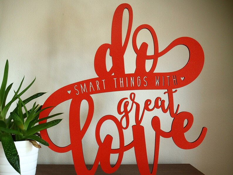 May include: Red wooden sign with the words "Do Smart Things With Great Love" in a cursive font.