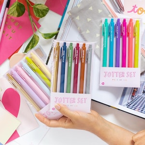 May include: Two sets of colorful pens with motivational quotes. The pens are packaged in clear plastic and labeled "Jotter Set, Pack of Six".