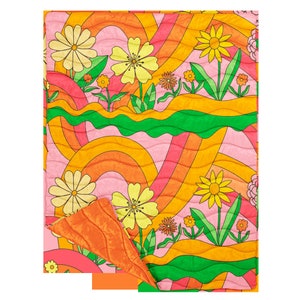 puffy quilted blanket with big colorful flowers and rainbow swirls with a solid color on the backside