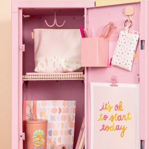Pale pink pouch inside a pink locker with other items.