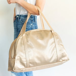 Young woman standing with metallic gold vegan leather back on her arm.