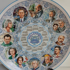 Könnte beinhalten: Dekorative weiße Platte mit blauem Blumenrand, die Porträts historischer Persönlichkeiten und einen Kalender für das Jahr 2000 zeigt. Die Platte trägt die Aufschrift "Millennium 2000 Art & Music."