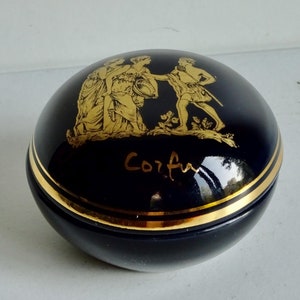 May include: A black ceramic trinket box with gold trim and a gold image of three figures and the word "Corfu" on the lid.