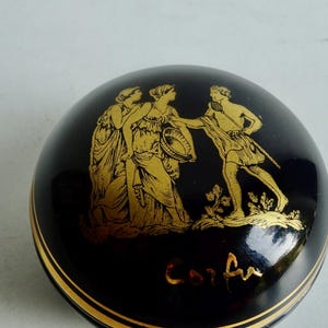 May include: A black and gold ceramic trinket box with a Greek mythological scene and the word "Corfu" inscribed on the bottom.
