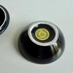 May include: A black ceramic bowl with a gold rim and a gold sticker on the bottom that reads "Special Scheria 24 K Gold Corfu".