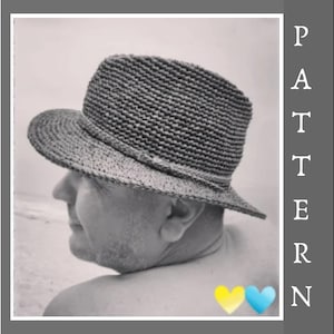 May include: A black and white photo of a person wearing a wide-brimmed straw hat. The person is facing away from the camera and is standing on a beach.
