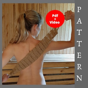 May include: A woman is holding a crocheted exfoliating body scrub made of natural fibers. The scrub is brown and has a textured pattern. The woman is in a sauna or spa setting. The image includes the text "Pdf + Video" in a red circle.