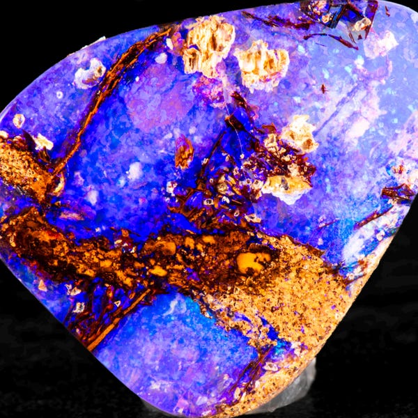 Peut inclure: Une pierre d'opale polie avec un affichage vibrant de couleurs. La pierre présente une base de teintes bleu foncé et violet, accentuée par des taches d'inclusions brun doré et crème. L'opale est posée sur un fond noir.