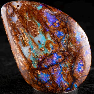 May include: A polished, teardrop-shaped opal displays a rich tapestry of colours. The gemstone features a base of deep brown, interwoven with vibrant blue and turquoise veins. The surface has a glossy finish, highlighting the natural patterns.