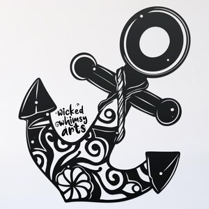 Könnte beinhalten: Schwarzer Anker aus Metall mit einem dekorativen, wirbelnden Muster. Der Anker hat ein Seildetail und der Text "wicked whimsy arts" ist auf dem Anker sichtbar.