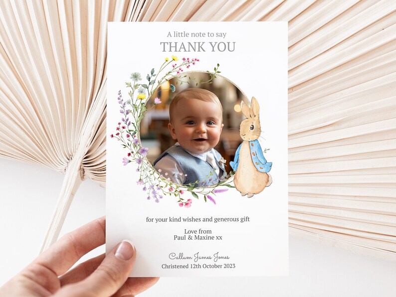 May include: A thank you card with a watercolour floral wreath and a photo of a baby boy. The card also features a cartoon illustration of Peter Rabbit. The text on the card reads "A little note to say THANK YOU for your kind wishes and generous gift. Love from Paul & Maxine xx. Calluen James Jones Christened 12th October 2023."