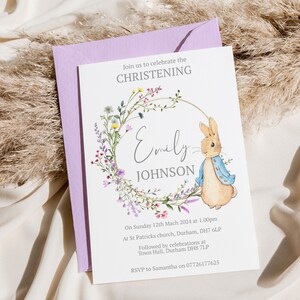 May include: A white card with a floral wreath and a rabbit illustration. The text reads "Join us to celebrate the Christening of Emily Johnson. On Sunday 12th March 2024 at 1:00pm at St Patricks church, Durham, DH7 6LP. Followed by celebrations at Town Hall, Durham DH8 7LP. RSVP to Samantha on 07726177625."