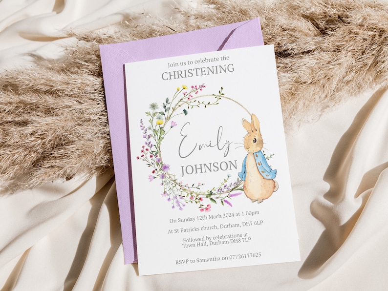 May include: A white card with a floral wreath and a rabbit illustration. The text reads "Join us to celebrate the Christening of Emily Johnson. On Sunday 12th March 2024 at 1:00pm at St Patricks church, Durham, DH7 6LP. Followed by celebrations at Town Hall, Durham DH8 7LP. RSVP to Samantha on 07726177625."
