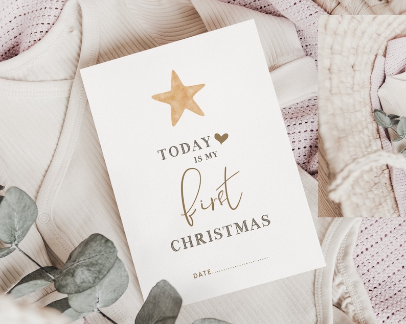 Pu&ograve; includere: Un biglietto bianco con il testo "TODAY IS MY first CHRISTMAS" e una stella dorata con un cuore sopra il testo. Il biglietto &egrave; su un tessuto a maglia bianco e rosa.