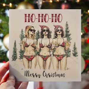 May include: A Christmas card featuring three women in Santa hats and bikinis holding drinks. The card has a beige background with a snowy scene and the text "Ho-Ho-Ho Merry Christmas".