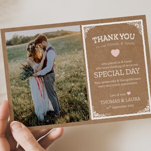 May include: A rustic brown thank you card with a white border and a photo of a bride and groom in a field. The text on the card reads "Thank you to our friends & family who joined us & those who were thinking of us on our special day. Your generosity & thoughtfulness were very much appreciated. Lots of love Thomas & Laura 12th September 2021 Hall."