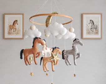 May include: A hanging nursery mobile featuring felt horses in brown, white, and gray, suspended from a circular wooden frame. The mobile includes white felt clouds, a gold crescent moon, and small gold stars hanging on white strings.