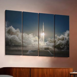 May include: A multi-panel canvas print depicting a rocket launch. The image shows a rocket ascending through a cloud of smoke and vapor against a blue sky. The artwork is displayed above a wooden cabinet.