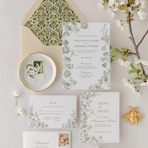 May include: Elegant wedding stationery set featuring floral designs in green and white. Includes invitations, RSVP cards, envelopes, and a "Save the Date" card. A decorative gold bee and floral accents complete the arrangement.