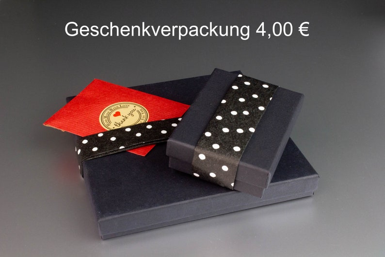 May include: A gift box set with a black box, a red card, and a black ribbon with white polka dots. The red card has a gold sticker with a heart and the words "thank you".