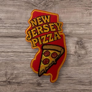May include: Embroidered patch in the shape of New Jersey, with the words "NEW JERSEY PIZZA" in gold lettering. A slice of pizza with pepperoni is featured at the bottom. The patch is red with a gold border.