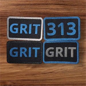 May include: Four black and white patches with blue trim. Two patches say "GRIT" in blue lettering. One patch says "GRIT" in gray lettering. One patch says "313" in blue lettering.