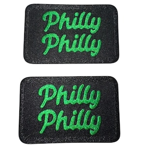May include: Two black rectangular patches with the text "Philly" written twice in green cursive lettering.