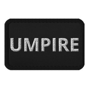 Può includere: Toppa ricamata nera con cuciture bianche che recita "UMPIRE".