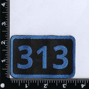 Pode incluir: Um remendo bordado preto e azul com o número 313 em azul.