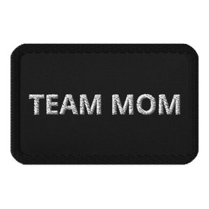 May include: Black embroidered patch with white text that reads "TEAM MOM".