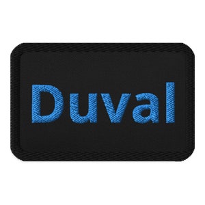 May include: Black rectangular patch with the word "Duval" embroidered in blue thread.