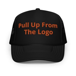 May include: Black trucker hat with a black mesh back. The hat has orange embroidered text that reads "Pull Up From The Logo".