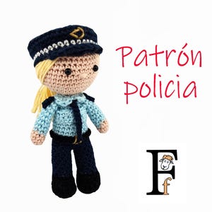 Puede incluir: Una muñeca de ganchillo hecha a mano vestida de policía, con un uniforme azul marino con una camisa azul claro y un sombrero a juego. La muñeca tiene el pelo rubio y ojos negros. El texto "Patrón Policia" está escrito en rojo.