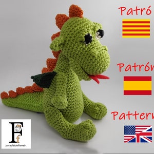 Puede incluir: Juguete de dragón de crochet verde con púas naranjas y un ala verde. El juguete tiene ojos negros y una lengua roja. La imagen también incluye las palabras "Patró", "Patrón" y "Pattern" en diferentes idiomas con las banderas correspondientes.