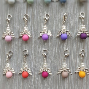 May include: Ten silver angel charms with different colored beads. The beads are pink, purple, orange, red, gray, and yellow.