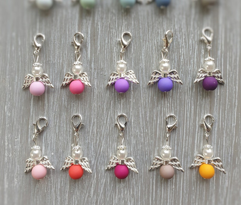 May include: Ten silver angel charms with different colored beads. The beads are pink, purple, orange, red, gray, and yellow.
