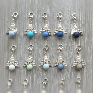 May include: Twelve silver angel charms with different colored beads. The beads are light blue, turquoise, dark blue, gray, light green, and brown.